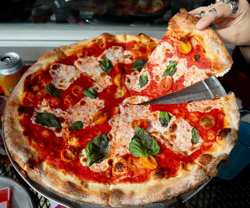 A Margherita pizza with fresh mozzarella, basil, and red and yellow baby tomatoes